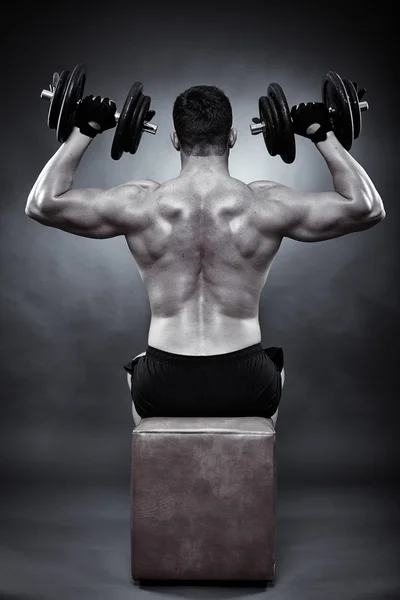 Athletic young man working with heavy dumbbells — Stock Photo, Image