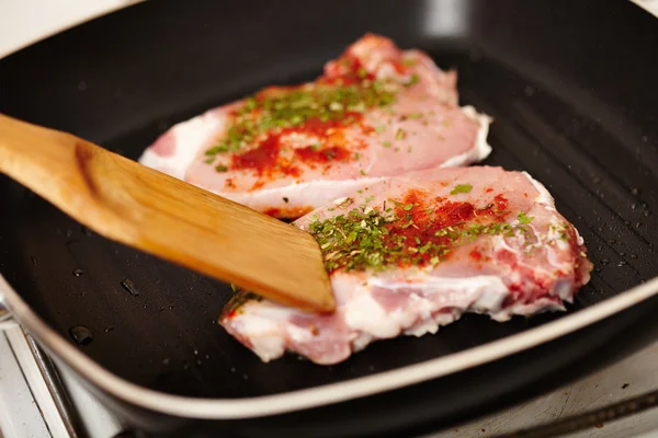 Cokk's hand preparing a spiced pork chop in the frying pan — Stock Photo, Image