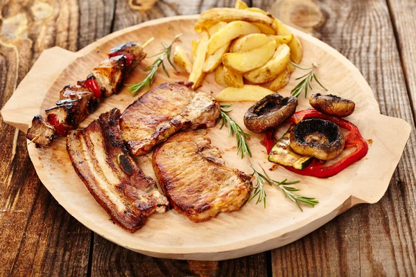 Carne de cerdo frita con cuñas de patatas y verduras a la parrilla — Foto de Stock
