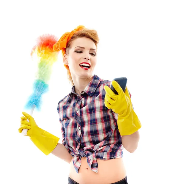 Dona de casa segurando um espanador e olhando para um telefone celular — Fotografia de Stock