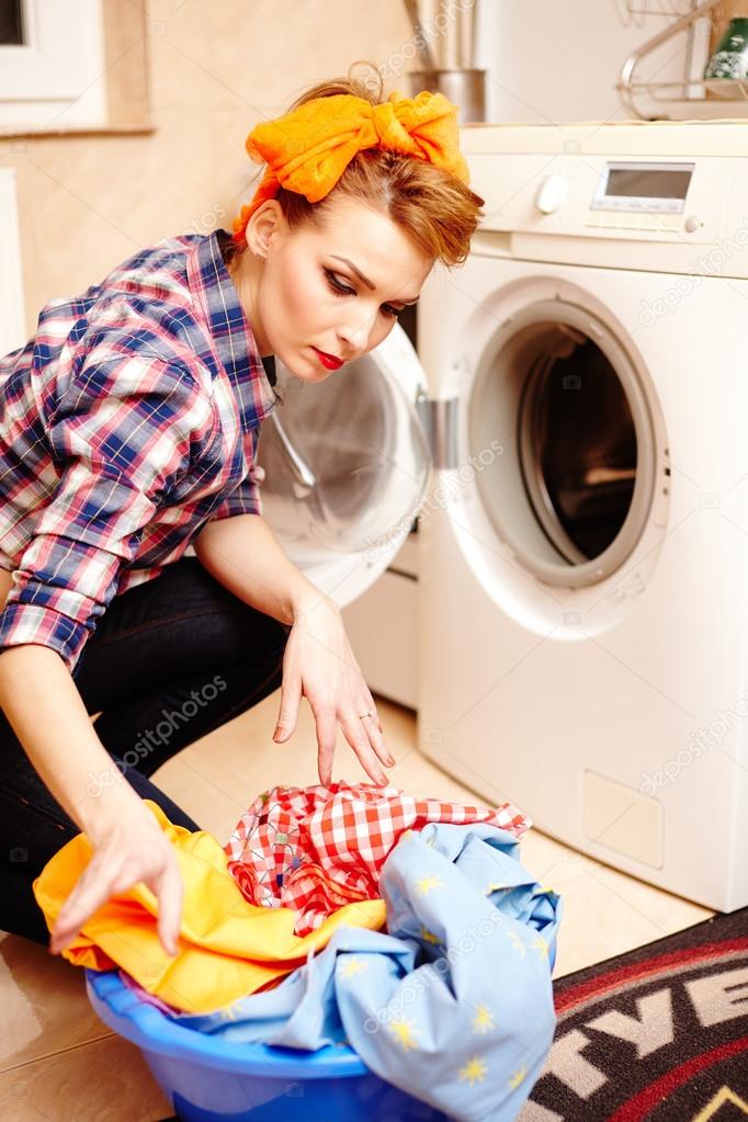 Housewife putting the laundry into the washing machine