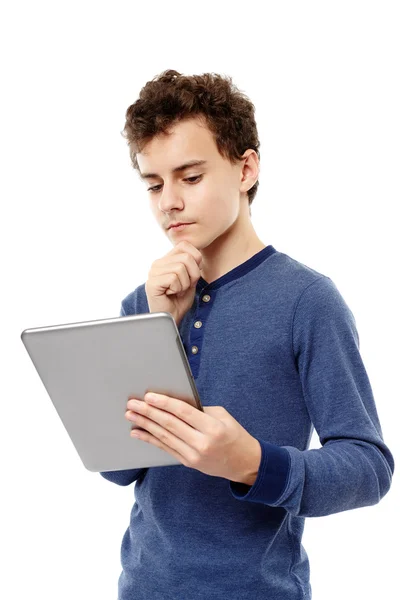 Adolescente inteligente trabalhando em um tablet que ele está segurando com a mão em ch — Fotografia de Stock
