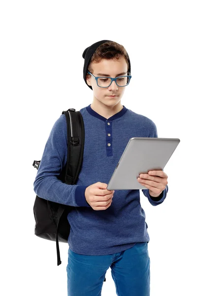 Adolescente na moda com mochila trabalhando em um tablet que ele está segurando — Fotografia de Stock