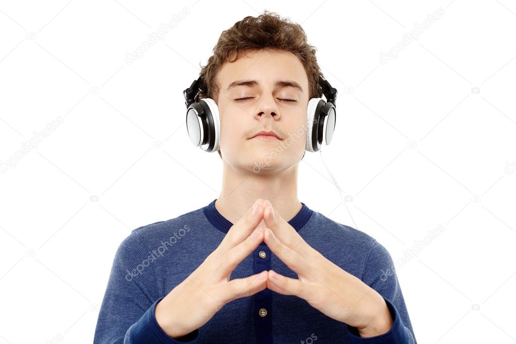 Relaxed teenager listening to music at headphones with eyes clos