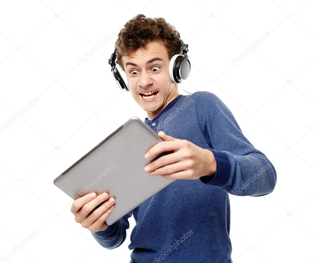 Angry teenager listening to music at headphones while looking at