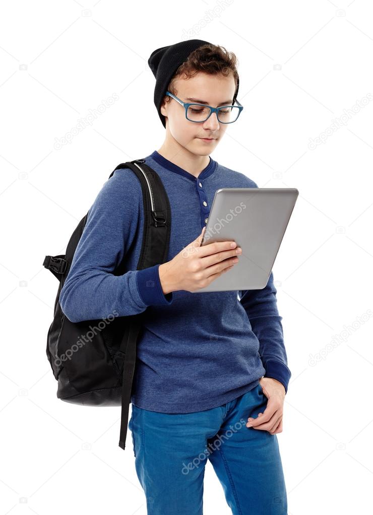 Trendy teenager with backpack working on a tablet he is holding