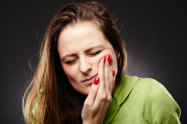 Young woman having a severe tooth ache with hand on cheek