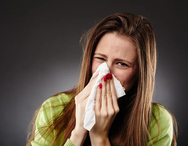 Caucasian female with flu blowing her nose Royalty Free Stock Photos