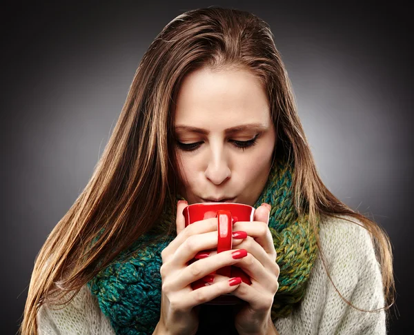 Woman with flu wrapped up in a scarf and drinking hot tea — Stock Photo, Image
