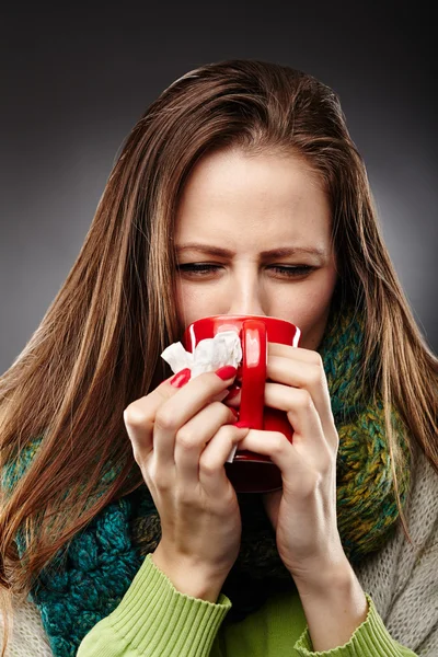 Kvinna känner sig sjuk med förkylning, insvept i en ullig halsduk och Royaltyfria Stockfoton