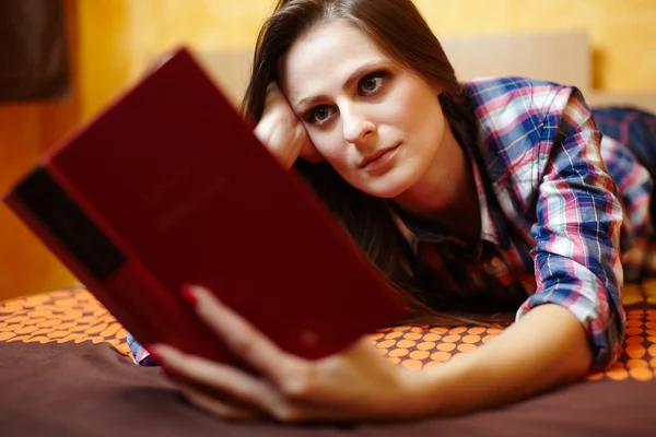 Jonge dame lezen van een boek op het bed — Stockfoto