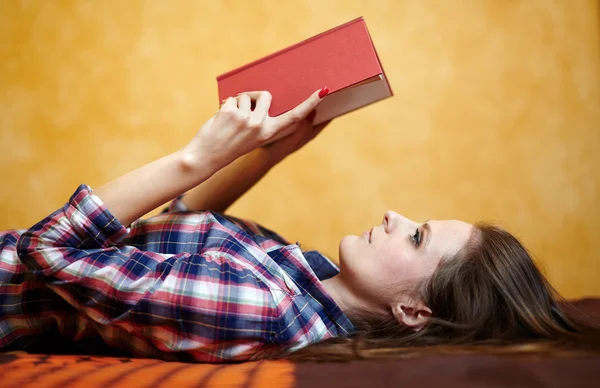 Νεαρή κοπέλα, διαβάζοντας ένα βιβλίο στο κρεβάτι — Φωτογραφία Αρχείου