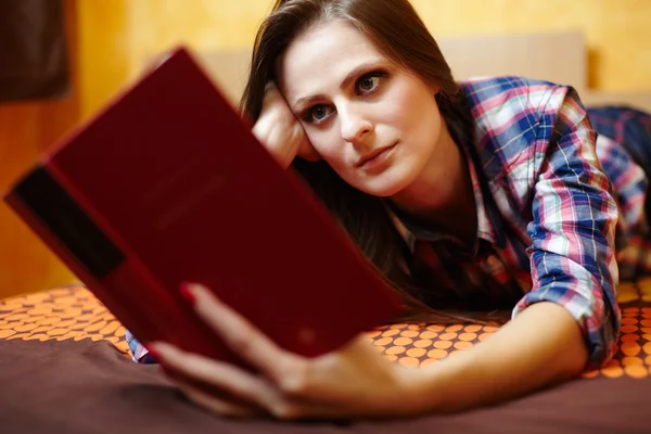 Νεαρή κοπέλα, διαβάζοντας ένα βιβλίο στο κρεβάτι Royalty Free Εικόνες Αρχείου