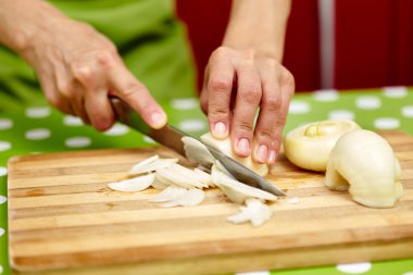 Woman slicing onion on a wooden board clipart
