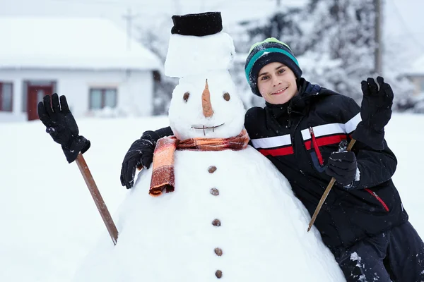 Teenager budování sněhulák — Stock fotografie