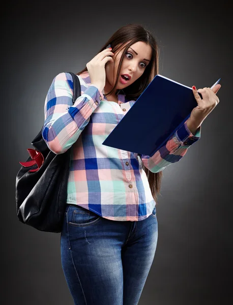 Étudiant inquiet lisant un cahier et parlant au téléphone — Photo