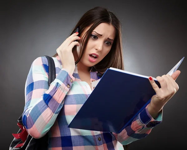 Bezorgd student lezen van een notebook en praten met de telefoon — Stockfoto