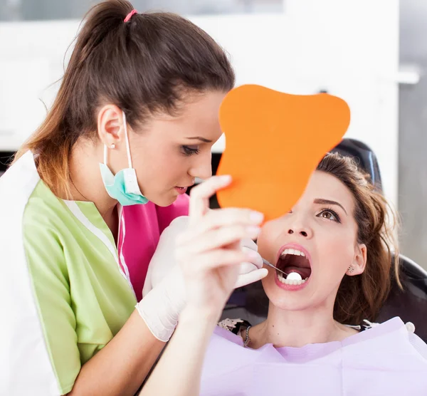 Patient looking in the mirror at her teeth — Stock Photo, Image