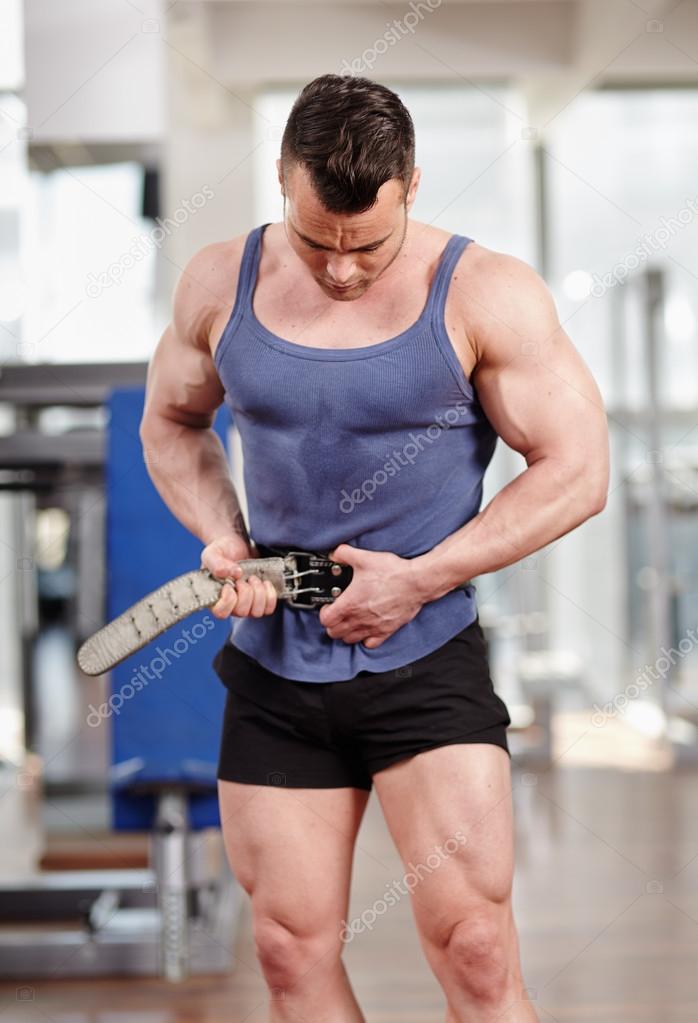 Man fastening belt in the gym