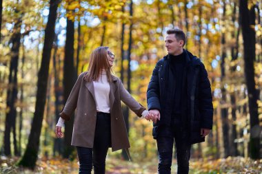 Sonbaharın ortasında meşe ormanında genç bir çift.