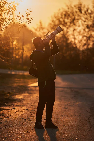 日没時にカメラと望遠レンズを持つプロの野生動物の写真家 — ストック写真