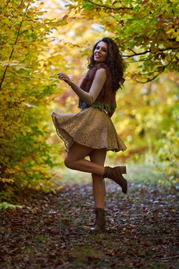 Ormanda sonbahar renkli ağaçlarla çevrili güzel, mutlu genç bir kadın.