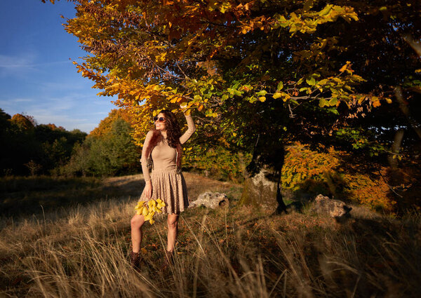 Beautiful young woman at sunset in autumn colors by the forest