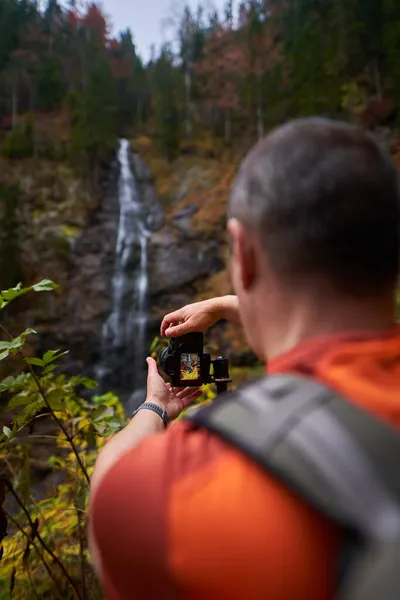 山の中でカラフルな秋の環境で滝を撮影するプロの自然写真家 — ストック写真