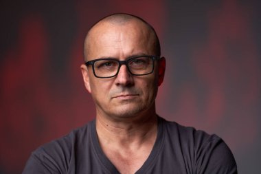 Geçmişi bulanık, gözlüklü, ciddi bir adamın yakın çekimi.