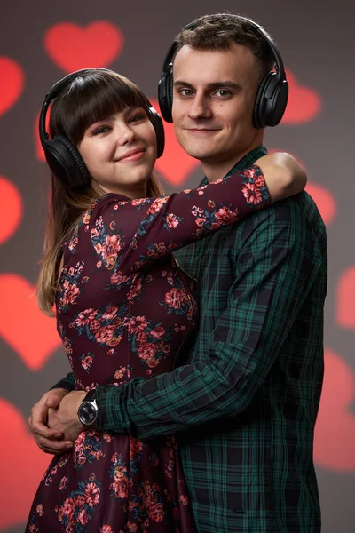 若い素敵なカップルが一緒に音楽を聞いていますヘッドフォンで心の背景 バレンタインデーのテーマ — ストック写真