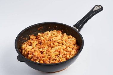A wok pan with tuna and fusilli pasta isolated on white background