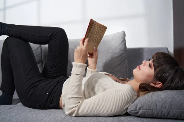 Young Woman Sitting Sofa Home Reading Book — Stock fotografie