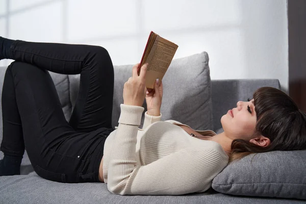 Young Woman Sitting Sofa Home Reading Book — ストック写真