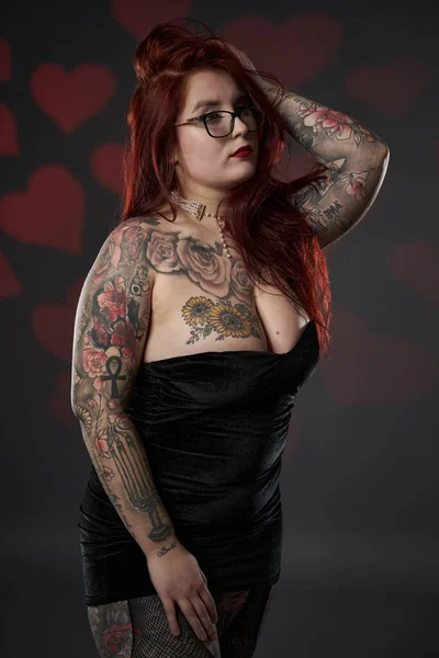 Beautiful size plus woman with tattoos in black mini dress, inclusiveness and body acceptance