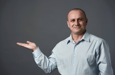 Olgun iş adamı, görünmeyen bir ürünü resmin yan tarafına sunuyor.