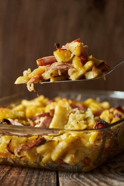 Patatesli domuz jambonu, parmesan ve cam tepside otlar, fırında fırın.