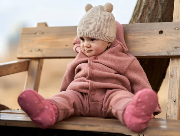 小さな赤ちゃんの女の子は公園の木製のベンチに座って — ストック写真