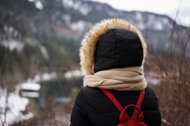 Dağlara bakan kışlık ceketli bir turist bayanın arkası.