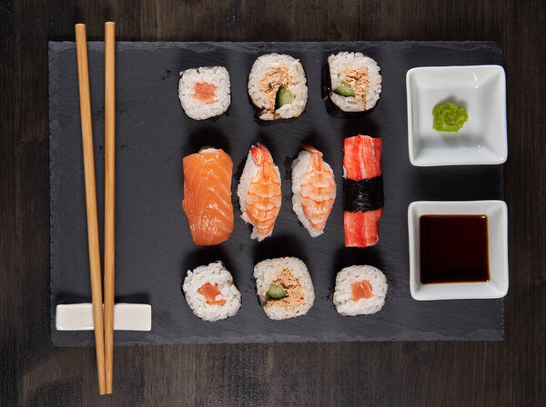 Sushi assortments served with soy and wasabi on a black stone