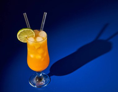 Buzlu turuncu alkolsüz kokteyl, mavi üzerine ferahlatıcı bir yaz içeceği.