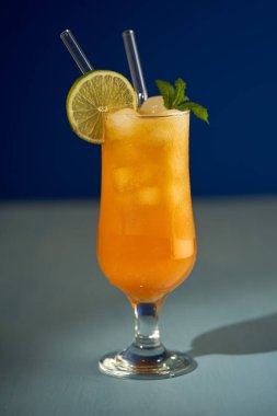 Buzlu turuncu alkolsüz kokteyl, mavi üzerine ferahlatıcı bir yaz içeceği.