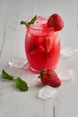 Ahşap bir tahtanın üzerinde kavanoz gibi bir bardakta çilek ile taze bir kokteyl.