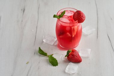 Ahşap bir tahtanın üzerinde kavanoz gibi bir bardakta çilek ile taze bir kokteyl.