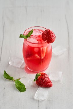 Ahşap bir tahtanın üzerinde kavanoz gibi bir bardakta çilek ile taze bir kokteyl.