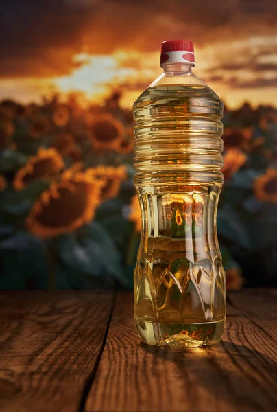 Butelka Olejkiem Słonecznikowym Drewnianej Desce Polem Słoneczników Zachodzie Słońca Tle — Zdjęcie stockowe