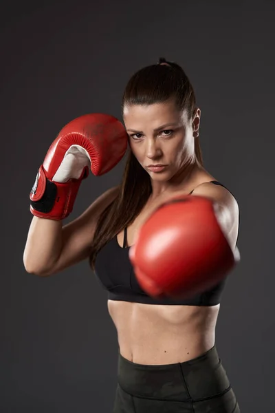 戴红色手套的女拳击手 带着刺拳 在灰色背景下被隔离 — 图库照片