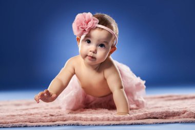 Şirin bir kızın ilk yılındaki yakın çekimi. Stüdyo mavi arka planda.