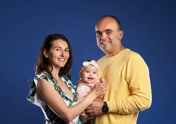 幸せな若いです家族とともに彼らの赤ちゃんの娘 スタジオは青の背景で撮影 — ストック写真