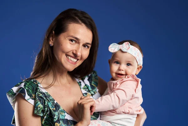 若いですお母さん持っています素晴らしい時間とともに彼女の赤ちゃんの娘 スタジオショットオーバー青の背景 — ストック写真