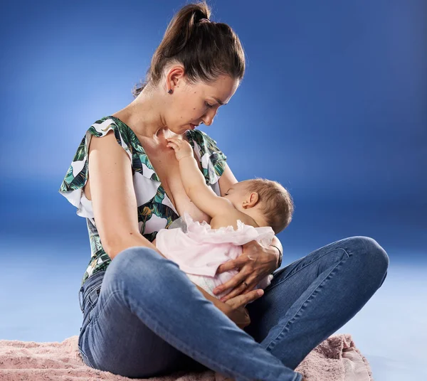 Junge Kaukasische Mutter Stillt Ihre Kleine Tochter Nahaufnahme Auf Blauem — Stockfoto